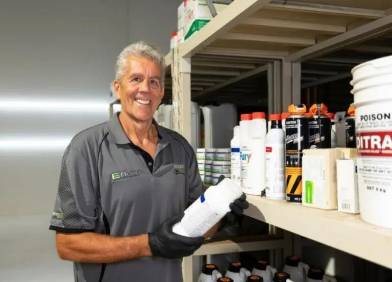 Man holding chemical container beside storage shelves