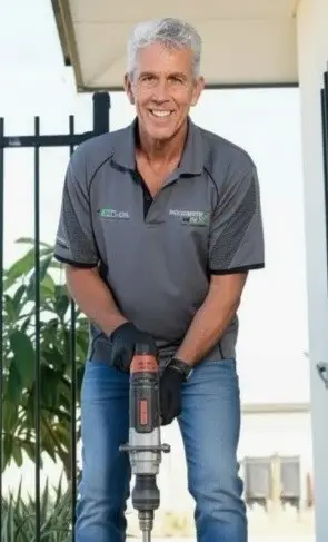 Smiling tradie using jackhammer outside home