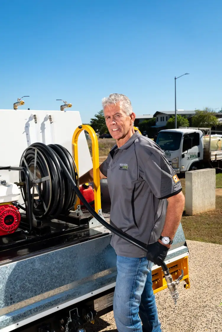 Technician operating high-pressure hose on service truck