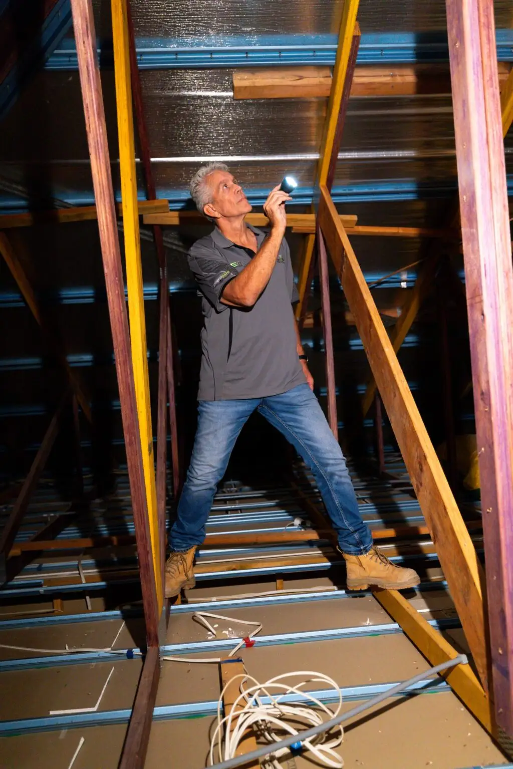 Man inspecting roof cavity with torch