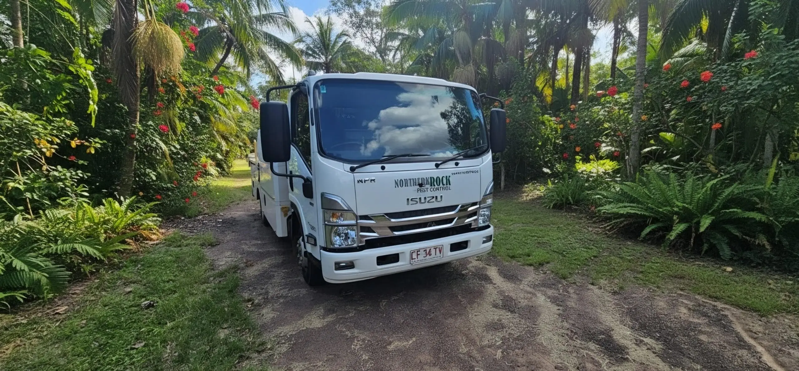 White pest control truck in tropical garden driveway