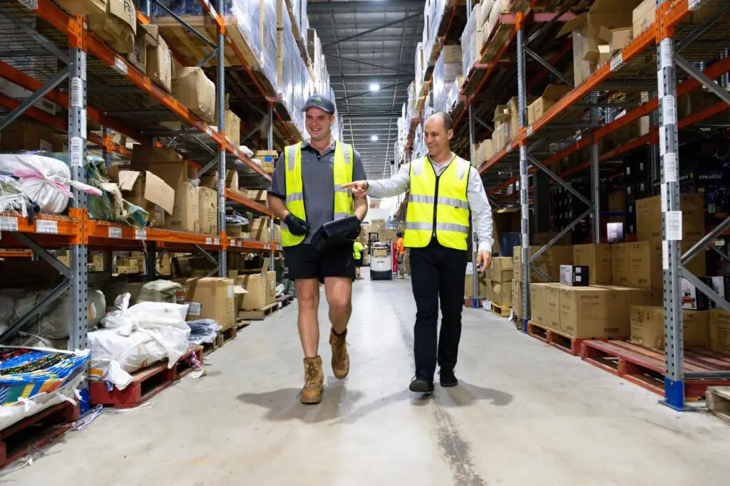 Warehouse workers in hi-vis vests checking stock